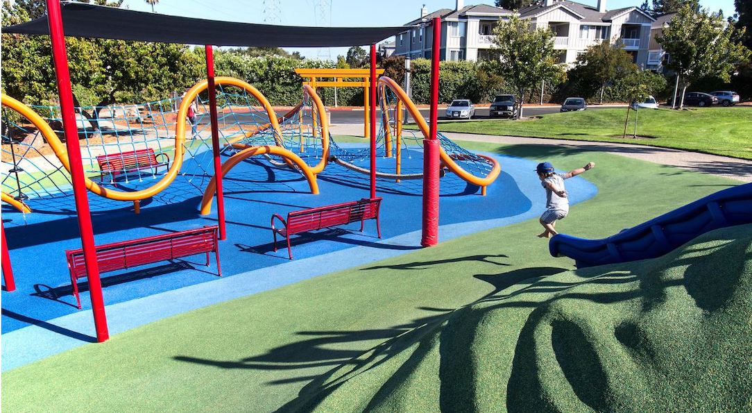 child jumping from slide onto rubber playground safety surfacing