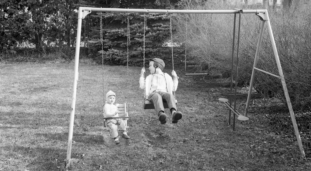 Two children swinging on a swingset