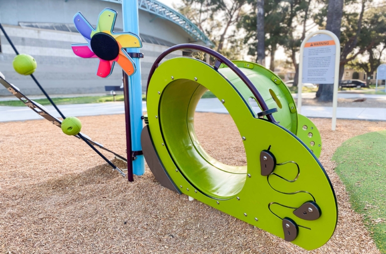 green playground equipment on wood shavings